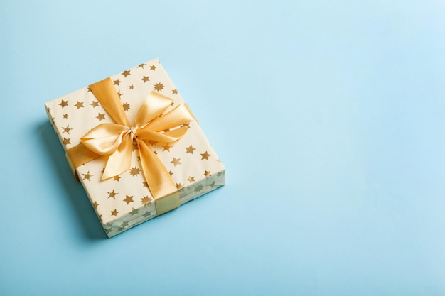 Navidad envuelta u otro regalo hecho a mano de vacaciones en papel blanco con cinta dorada sobre fondo de color Presente la decoración de la caja de regalo en la vista superior de la mesa de color con espacio de copia