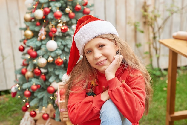 Navidad familiar en julio. Retrato de niña cerca del árbol de Navidad con regalos. Pino de decoración de bebé. Concepto de personas y vacaciones de invierno. Feliz Navidad y felices fiestas tarjeta de felicitación. Niño de navidad