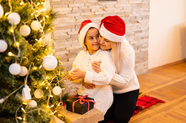 Navidad, feliz madre de familia con hija con regalos en la víspera de Navidad