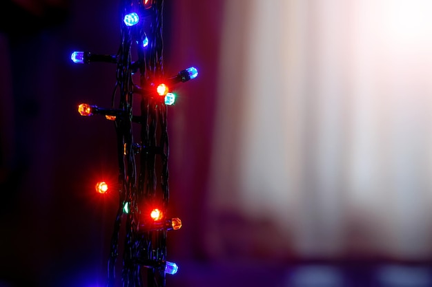 Navidad festiva y Año Nuevo con guirnaldas de luces de colores sobre fondo negro cerca del espacio de copia de la ventana