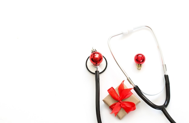 Navidad, Flatlay médico de Año Nuevo. Estetoscopio, regalo, adornos navideños sobre un fondo blanco. Copie el espacio.