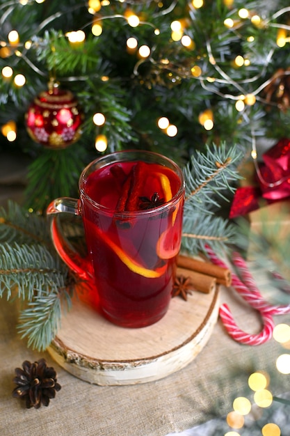 Navidad glasse de vino tinto caliente con naranjas anís cerca de regalos luces de Navidad en el fondo