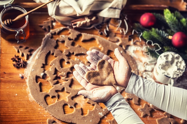 Navidad para hornear y corazón de pan de jengibre en manos de mujer.