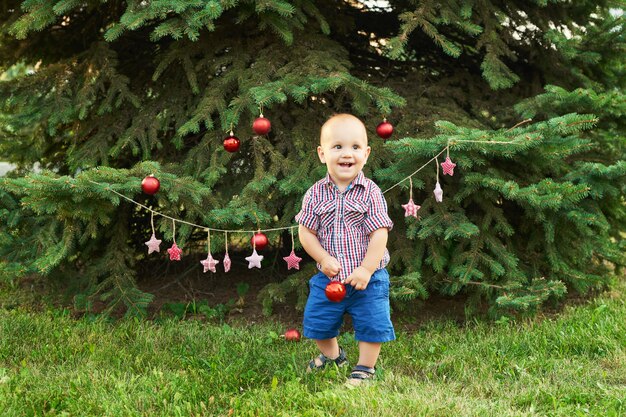 Navidad en julio, baby boy en navidad. rodando en el verano en el parque, decoración de año nuevo