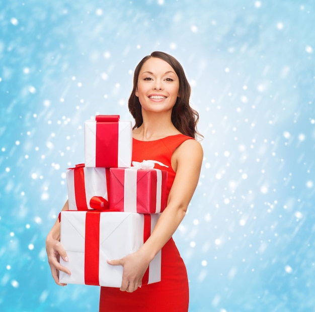 Navidad, Navidad, día de San Valentín, concepto de celebración - mujer sonriente en vestido rojo con muchas cajas de regalo