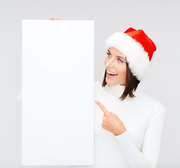 Navidad, Navidad, gente, publicidad, concepto de venta - mujer feliz con sombrero de ayudante de santa con pizarra en blanco