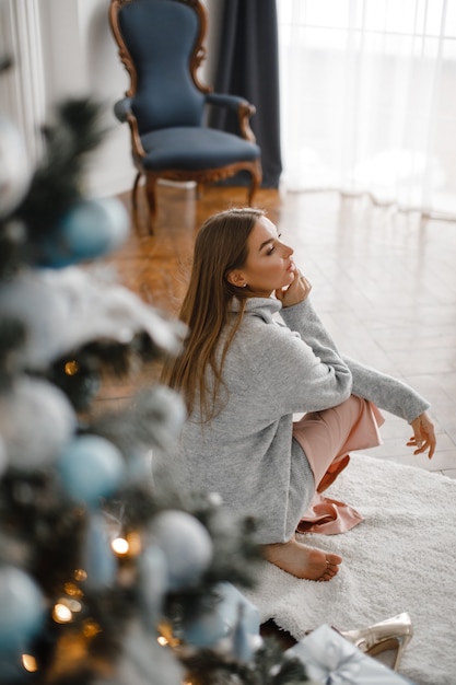 Navidad, Navidad, invierno, concepto de felicidad - mujer sonriente con muchas cajas de regalo. Chica abre un regalo en el contexto del árbol de Navidad. feliz, mujer joven, celebrar, navidad