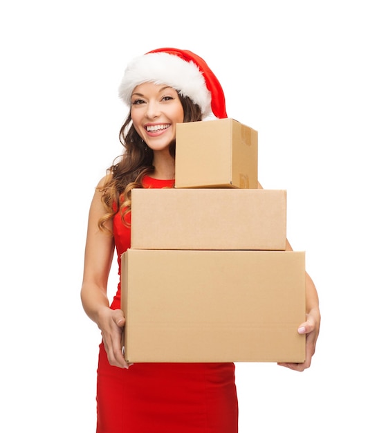 Foto navidad, navidad, invierno, concepto de felicidad - mujer sonriente con sombrero de ayudante de santa con muchas cajas de paquetería