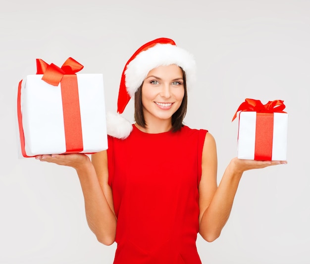 Navidad, Navidad, invierno, concepto de felicidad - mujer sonriente con sombrero de ayudante de santa con muchas cajas de regalo