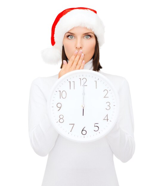 Navidad, Navidad, invierno, concepto de felicidad - mujer sonriente con sombrero de ayudante de santa con reloj mostrando 12