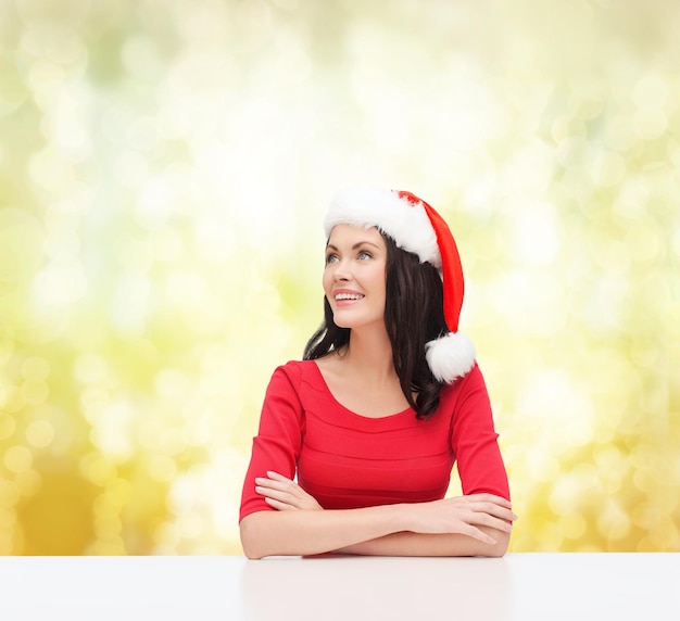 Navidad, Navidad, invierno, concepto de felicidad - mujer sorprendida con sombrero de ayudante de santa mirando hacia arriba