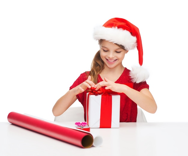 Navidad, Navidad, invierno, concepto de felicidad - niña sonriente con sombrero de ayudante de santa con caja de regalo