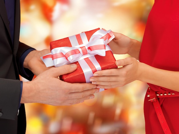 Navidad, Navidad, invierno, vacaciones, concepto de felicidad - manos de hombre y mujer con caja de regalo