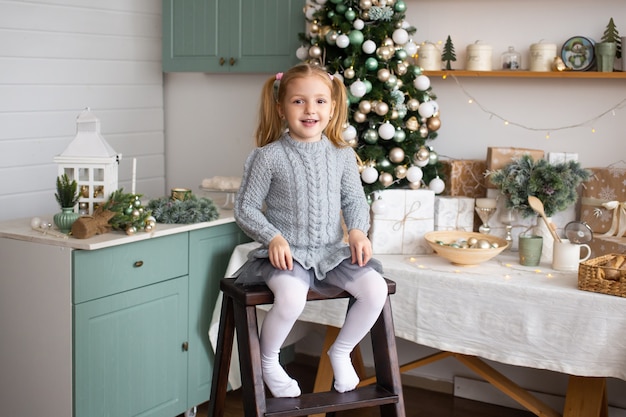 Navidad niña está sentada en la cocina en casa