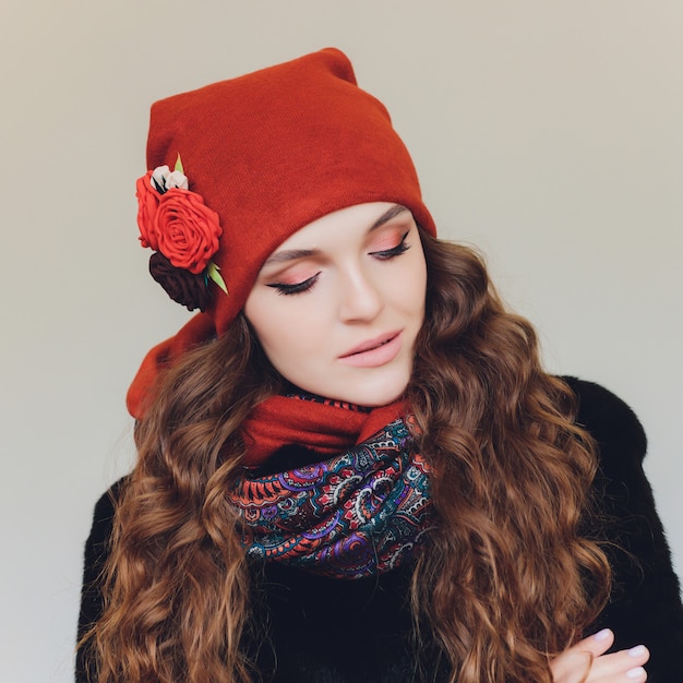 Navidad niña vistiendo gorro de punto y guantes, aislados en gris