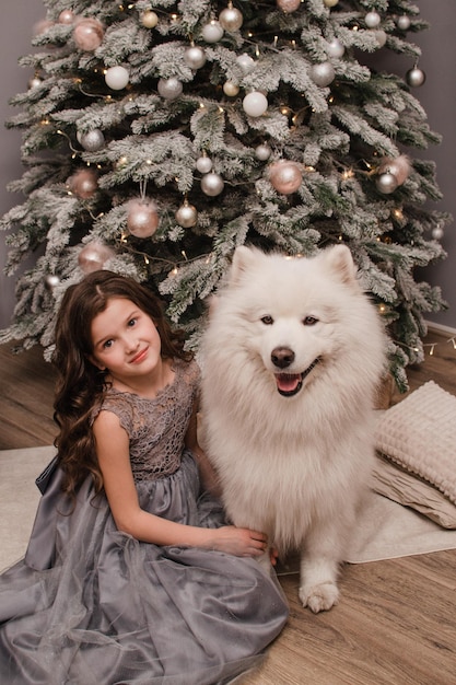 Navidad Niño niña abrazo perro Samoyedo. Concepto de Navidad, invierno y personas.