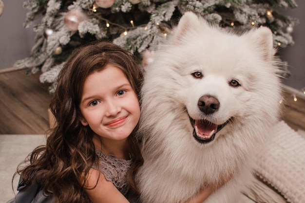 Navidad Niño niña abrazo perro Samoyedo. Concepto de Navidad, invierno y personas.