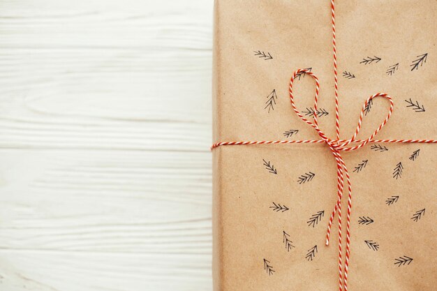 Foto navidad plana pone elegante regalo con cinta roja y patrón de árbol espacio de copia regalo artesanal moderno sobre fondo blanco de madera maqueta de tarjeta de saludos de temporada espacio de copia