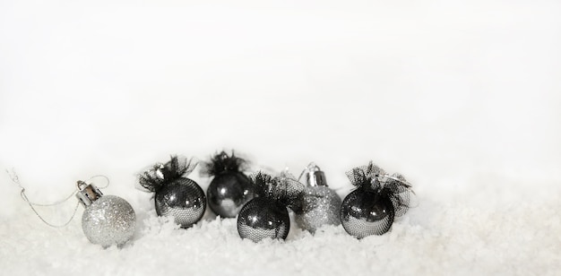 Navidad plata y globos negros y nieve sobre un fondo blanco.