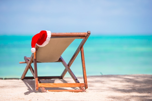 Navidad en la playa - silla con sombreros de Santa en el mar. Concepto de vacaciones de navidad