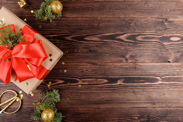 Navidad con regalo artesanal con cinta roja, ramitas de abeto decoración navideña dorada en madera