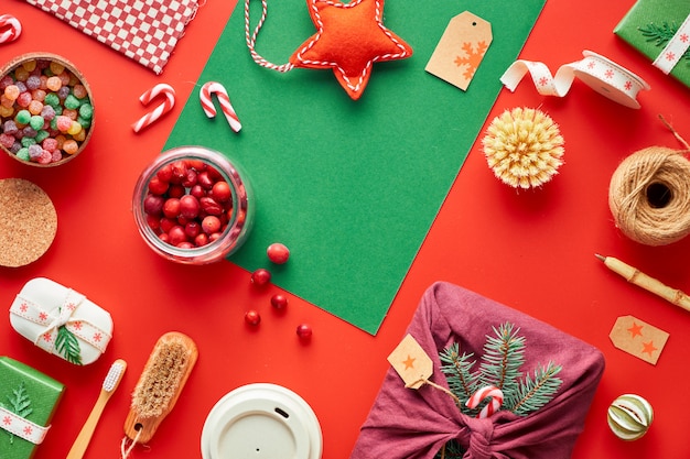 Navidad roja y verde. Moda ecológica cero desperdicio decoraciones y regalos de Navidad y Año Nuevo. Plano geométrico con regalos, cajas decoradas, taza de café de bambú y bastones de caramelo.