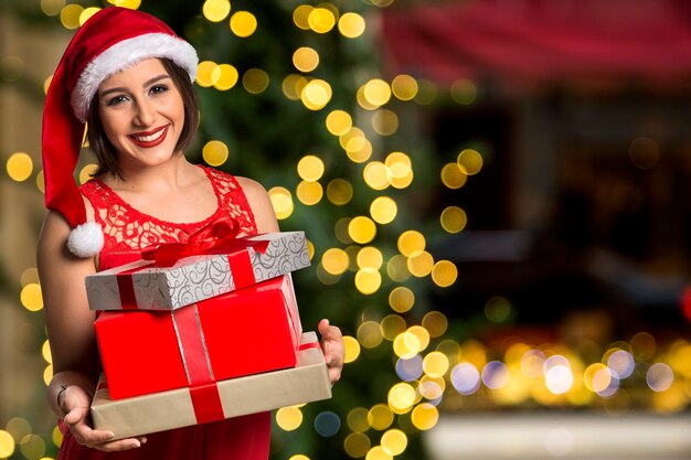 Navidad Santa sombrero aislado mujer retrato mantenga regalo de Navidad. Sonriente niña feliz sobre fondo de Navidad