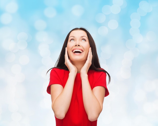 navidad, vacaciones, día de san valentín, celebración y concepto de la gente - mujer sonriente vestida de rojo sobre fondo de luces azules