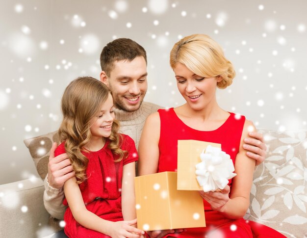 navidad, vacaciones, felicidad y concepto de la gente - familia sonriente mirando una caja de regalo abierta en casa