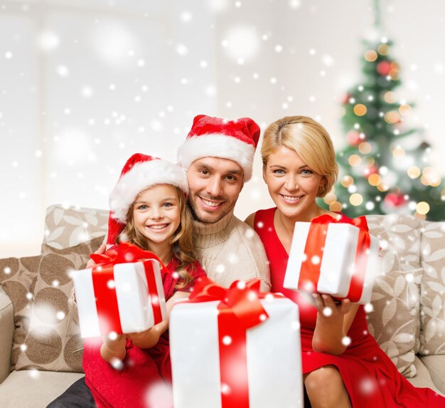 navidad, vacaciones, felicidad y concepto de la gente - familia sonriente con sombreros de ayudante de santa con muchas cajas de regalo en casa