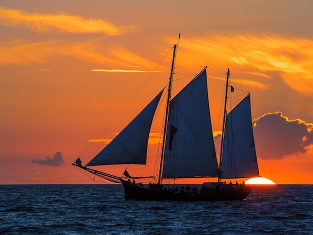 Foto navio a navegar no mar contra o céu durante o pôr-do-sol