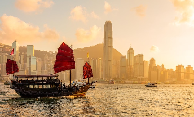 Navio chinês de velas vermelhas de madeira no porto de Hong Kong Victoria na hora do pôr do sol