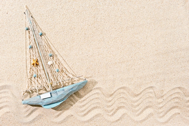 Navio de brinquedo de madeira na areia, vista superior, espaço de cópia
