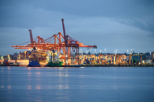 Foto navio de carga internacional com iluminação de carga de contêineres e guindastes de pórtico no porto