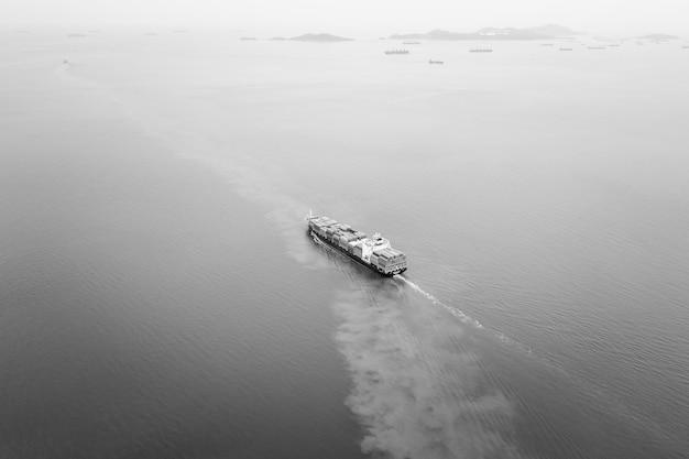 Navio porta-contentores de carga preto e branco navegando a toda velocidade em negócios de importação e exportação marítima