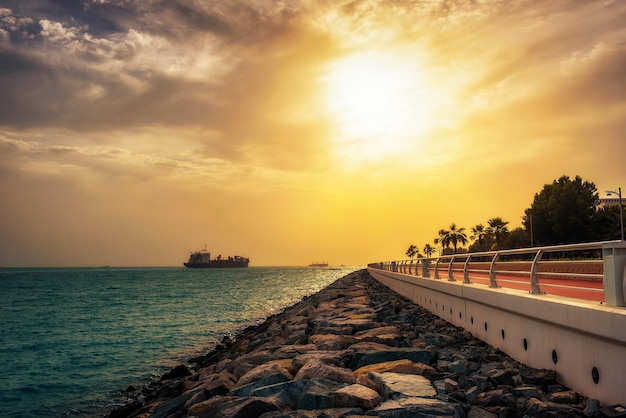 Navio porta-contentores de carga saindo da Marina de Dubai ao pôr do sol