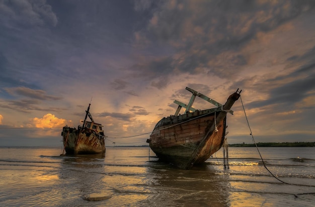 Navios abandonados contra o céu do pôr-do-sol