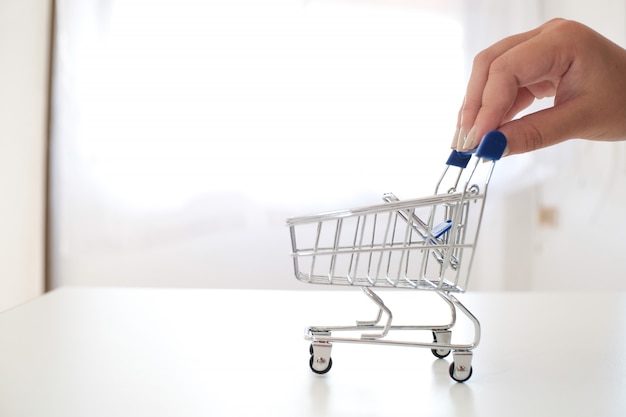 Índice de mano de mujer empujando carrito de compras pequeño