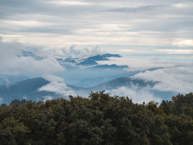 Nebel und Wolken bedecken die Wälder und geschichteten Berge