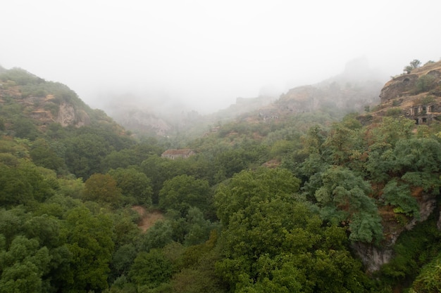 Nebelblick auf die alte Höhlenstadt Khndzoresk in den Bergfelsen Armeniens Landschaftsattraktion Verlassene Ruinen im Nebel Atmosphärische stockfotografie