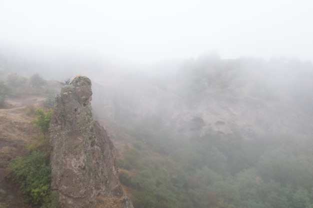 Nebelblick auf die alte Höhlenstadt Khndzoresk in den Bergfelsen Armeniens Landschaftsattraktion Verlassene Ruinen im Nebel Atmosphärische stockfotografie