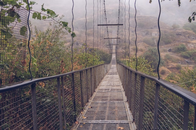 Nebelblick auf die Khndzoresk-Hängebrücke in der Höhlenstadt in den Bergfelsen Armeniens Landschaftsattraktion Verlassene Ruinen im Nebel Atmosphärisches stockfoto