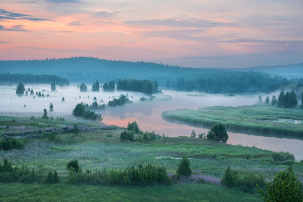 Nebelhafte Morgendämmerung am Fluss