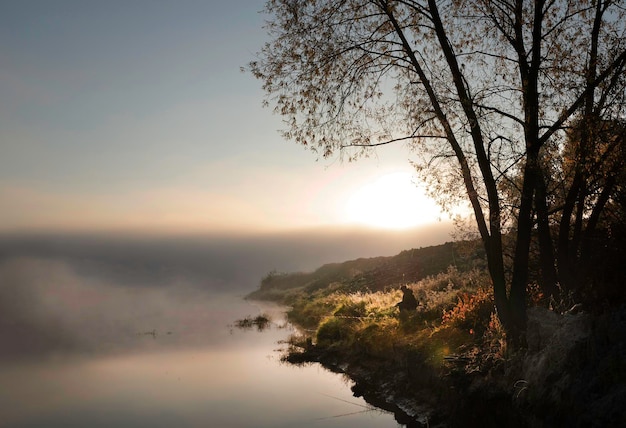 Nebelige Morgenlandschaft mit Fischern am Ufer