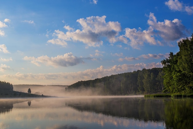 Nebeliges Flachland am Flussufer zur Sommersonnenaufgangszeit