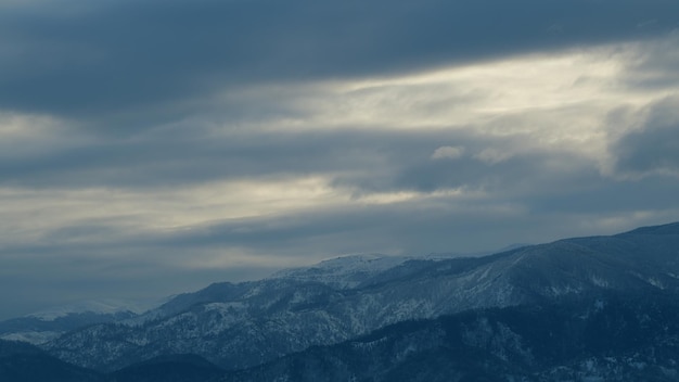 Nebelwolken über schneebedeckten Bergen Berggipfel, die an einem bewölkten Tag mit Schnee bedeckt sind