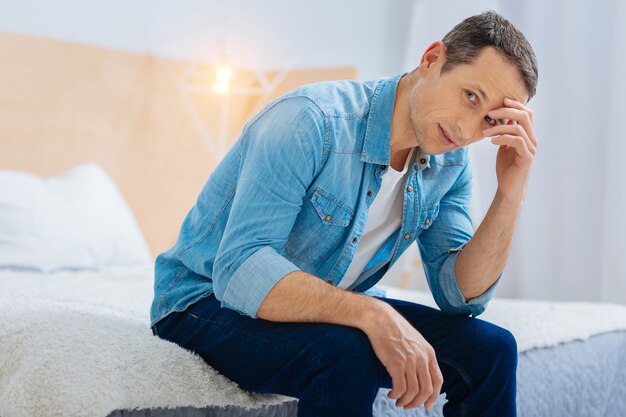 Foto necesidad de pensar. hombre atento que expresa positividad mientras apoya los codos en las piernas y gira la cabeza