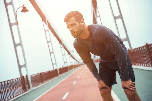 Necesito una vista trasera del freno de un joven apuesto en ropa deportiva relajándose mientras