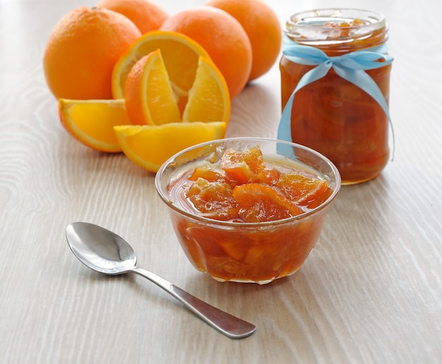 Néctar de las naranjas en un bol y una olla de naranja fresca en el fondo