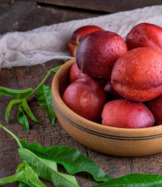 Nectarina de duraznos maduros en un tazón de madera marrón